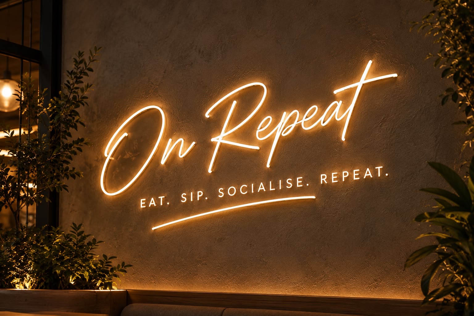 Warmly lit ON REPEAT sign inside the café concept